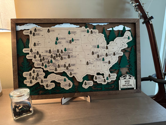 Map of United States with tree and skyline background. Every state with a National Park has tree cut out including Hawaii and Alaska that you can place back inside the cut out after your visit.